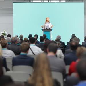 A speaker addressing a crowd of people at a conference.