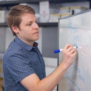 NAU Associate Professor, Joe Mihaljevic, writing on a white board.